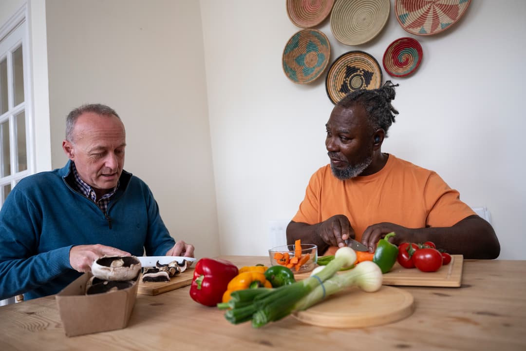 Two men cutting vegetables.